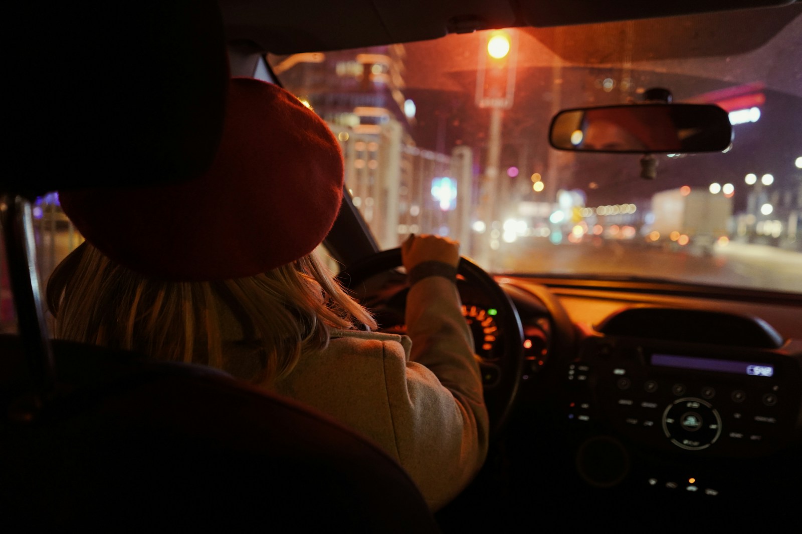 a woman driving a car at night on a city street, auto, sr-22